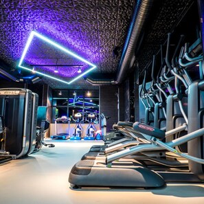 Un gimnasio con cintas de correr, elípticas y equipo de levantamiento de pesas.