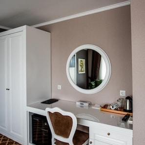 A compact hotel room with a white wardrobe, a round mirror, a small desk, and a chair. - Arpesos (Kardzali)