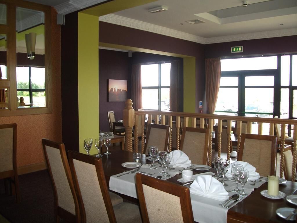 A dining area with tables set for four, chairs, and a large window with curtains.