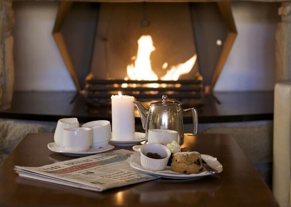 A table with a newspaper, a candle, a teapot, cups, and a plate with a pastry. - Broadhaven Bay Hotel (Belmullet)