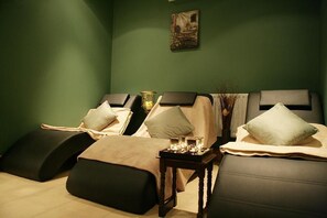 A spa room with three massage tables, each with a pillow and a small table with candles. - Broadhaven Bay Hotel (Belmullet)