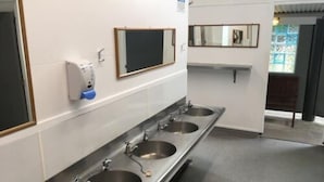 Eine öffentliche Toilette mit drei Waschbecken, einem Händetrockner und einem Spiegel.