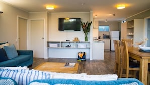 Ein modernes Wohnzimmer mit einer Couch, einem Couchtisch und einem an der Wand montierten Fernseher.