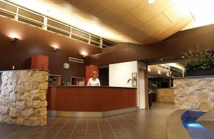 Uma área de recepção com recepcionista, paredes de pedra e uma área de piscina.