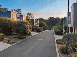 Una calle residencial con casas modernas, cielo despejado y jardines bien cuidados.