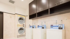 Une buanderie équipée de quatre machines à laver et d’un sèche-linge, chacun doté d’un panneau de commande.