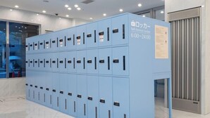 Une rangée de casiers bleus en libre-service, avec une pancarte indiquant qu’ils sont disponibles de 6 h 00 à 24 h 00.