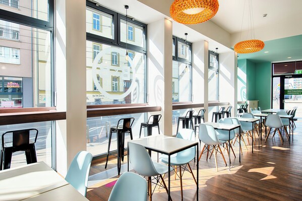 Ein modernes Café-Interieur mit großen Fenstern, verschiedenen Sitzbereichen und Blick auf die Straße.