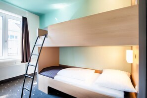 Una cama litera con escalera, una ventana con cortinas y una lámpara fijada a la pared.