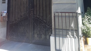 Une entrée d’immeuble agrémentée de détails architecturaux raffinés, une grande porte en métal et un petit appareil de climatisation fixé au mur.