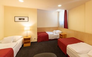 A hotel room with two beds, a bedside table with a lamp, a small shelf, and a framed picture on the wall. - Laterum Conference And Wellness (Pecs)