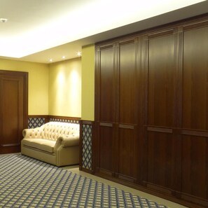 A room with a large wardrobe, a sofa, and patterned carpet. - Centrum Hotel Debrecen (Debrecen)
