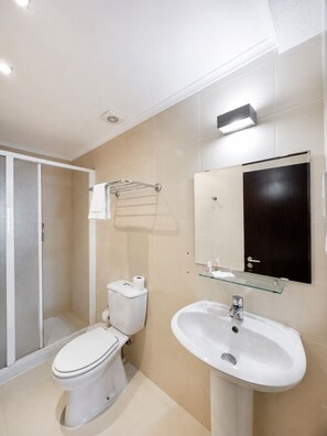 A modern bathroom with a toilet, sink, and glass shower enclosure. - Residencial Sao Francisco (Horta)