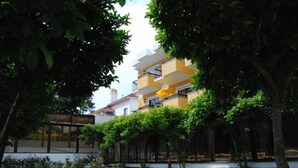 Un edificio de varios pisos con balcones, rodeado de vegetación y un césped bien cuidado.