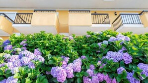 Un edificio con balcones y un seto verde exuberante.