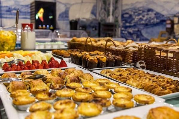 Een buffet met diverse gebakjes, fruit en brood.