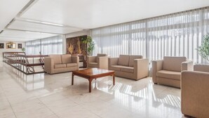 A spacious lobby with a central coffee table, multiple sofas, a staircase, and large windows with sheer curtains. - Crisol Tres Pastorinhos (Ourem)