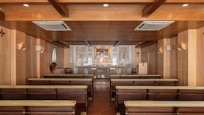 A church interior with wooden pews, a central altar, and religious icons. - Crisol Tres Pastorinhos (Ourem)