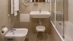 A compact bathroom with a bathtub, a sink, a vanity, and a toilet. - Residencial Miramar (Marinha Grande)