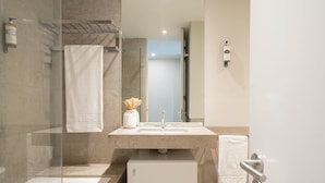 Une salle de bain moderne avec une douche à parois de verre, un lavabo blanc et un petit meuble blanc.