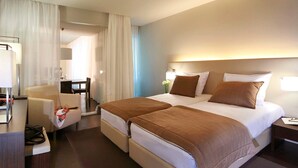 Une chambre d’hôtel avec un lit double, un bureau avec une chaise, une petite table et une lampe.