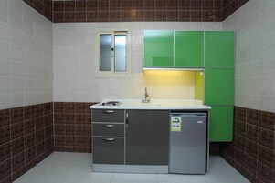 Una cocina compacta con fregadero, armarios y refrigerador.
