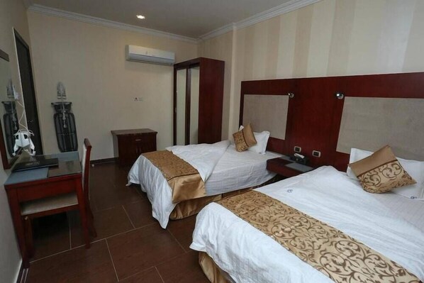A hotel room with two beds, a desk, and a chair. - Raoum Inn Serviced Apartments Hafar Al Batin (Hafr Al Batin)