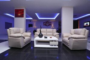 A modern living room with two beige sofas, a white coffee table, and a TV on the right wall. - Raoum Inn Serviced Apartments Hafar Al Batin (Hafr Al Batin)