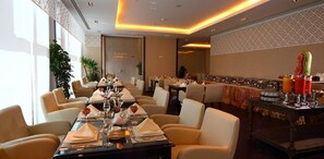 A restaurant with long tables, chairs, and a bar area with drinks. - Zara Continental Hotel (Al Khobar)