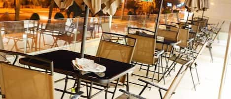 A row of empty tables with chairs, a glass partition, and umbrellas.