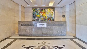 Un espace d’accueil doté d’un comptoir de réception en marbre et d’une peinture abstraite aux couleurs vives accrochée au mur.