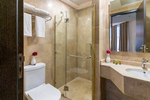 A modern bathroom with a glass-enclosed shower, a toilet, and a sink with toiletries. - Al Hidayah Towers Hotel (Makkah)