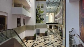 Un intérieur à plusieurs niveaux, avec un couloir central, des rampes en verre et un sol à motifs.
