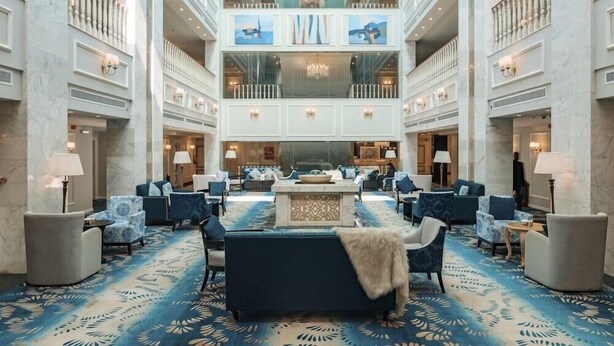 Eine großzügige Lobby mit einer zentralen Sitzgruppe, mehreren Etagen und einem Chandelier.