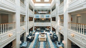 Ein geräumiges Atrium mit einer zentralen Sitzgruppe, hohen Decken und einer Glaskuppel.