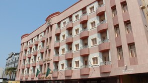 A multi-story hotel with balconies, a flag, and an entrance sign. - Gulf Park Hotel Apartment (Dammam)