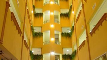 A multi-level atrium with a central swimming pool, balconies with railings, and decorative plants.