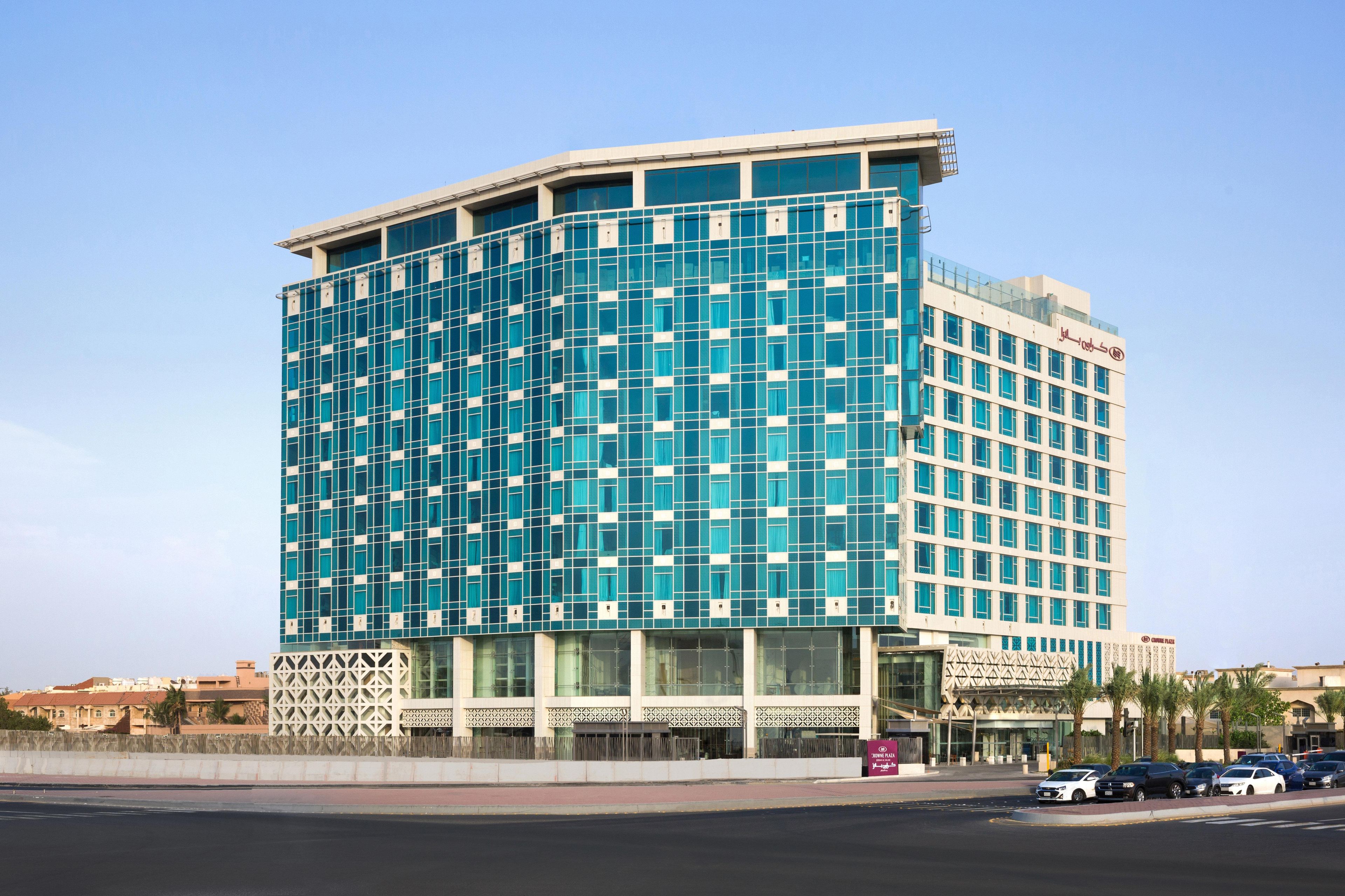 A modern hotel with a curved facade, large windows, and a prominent entrance.
