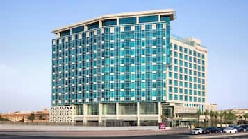 A modern hotel with a curved facade, large windows, and a prominent entrance.
