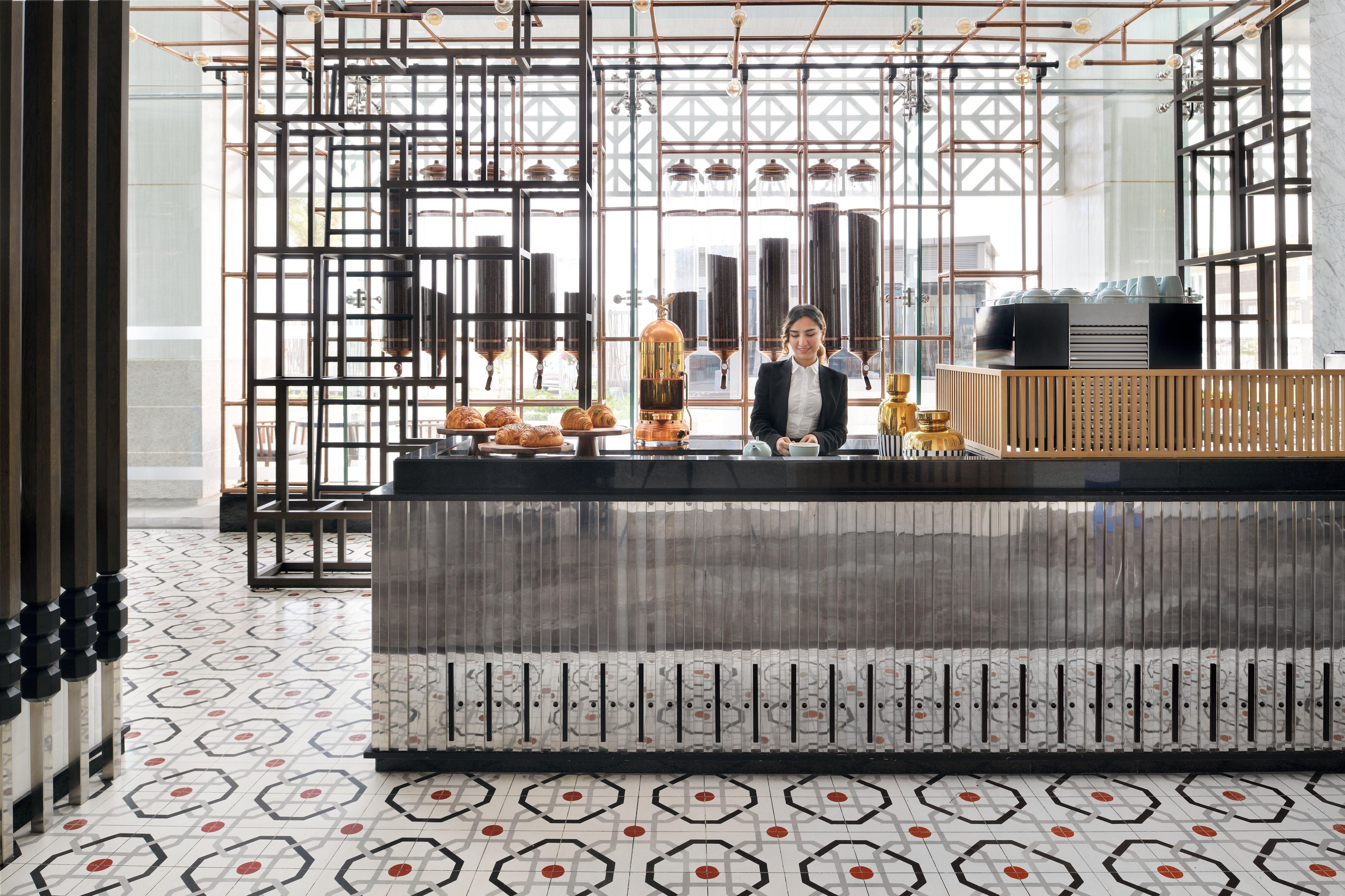 Um interior moderno com área de bar, piso com padrão geométrico e vista através de grandes janelas.