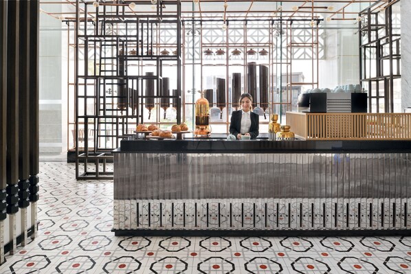 A modern interior with a bar area, geometric patterned flooring, and a view through large windows. - Crowne Plaza Jeddah Al Salam (Jeddah)
