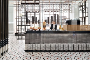 Un interior moderno con una zona de bar, suelo de estampado geométrico y vistas amplias a través de grandes ventanales.