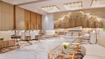 A spacious hotel lobby with a large seating area, a stage, and a decorative floral arrangement.