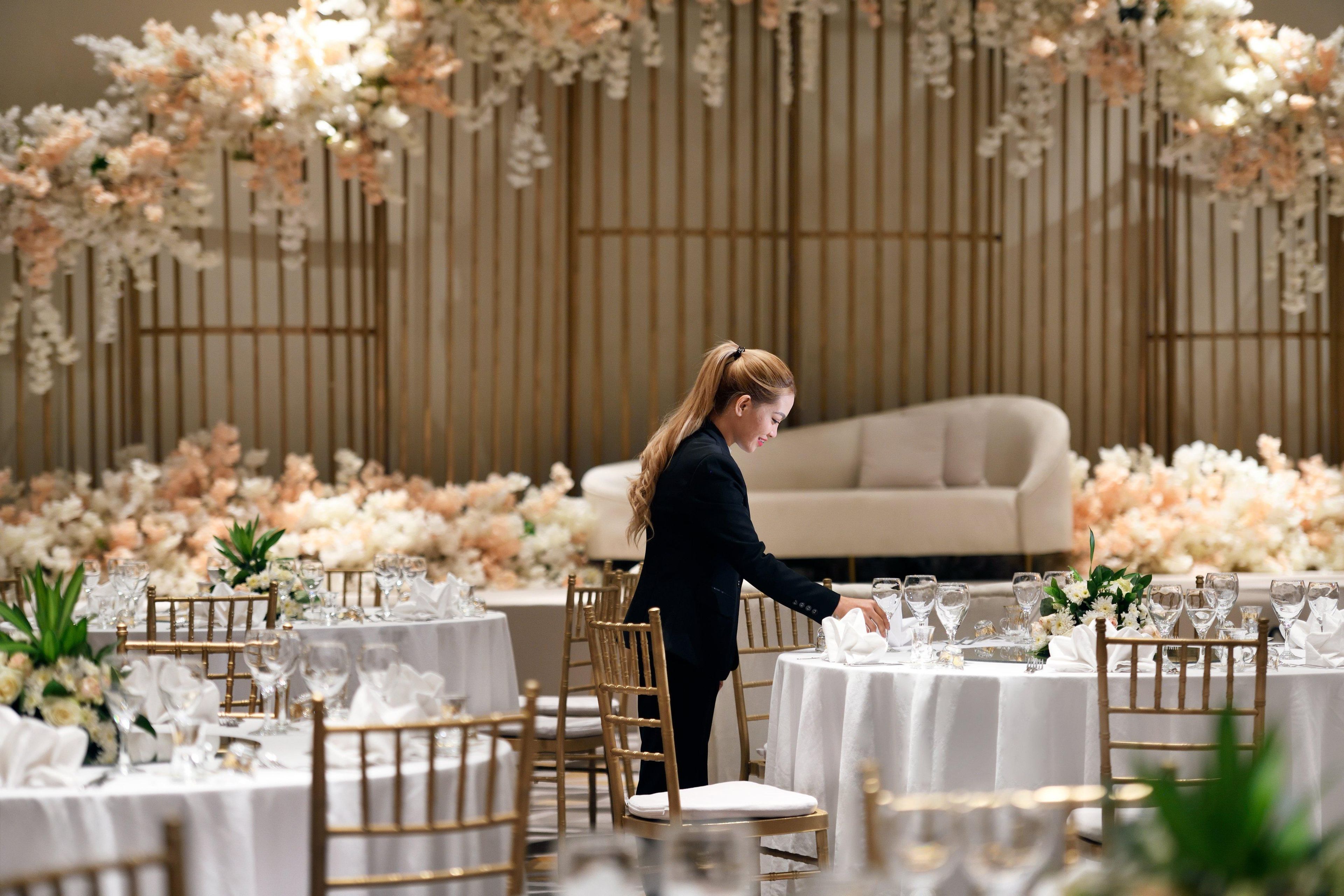 Un montaje formal para el comedor con mesas, sillas y un fondo floral.