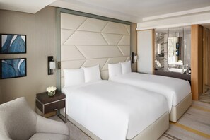 A hotel room with two beds, a nightstand, a chair, a wall-mounted lamp, and a mirror. - Crowne Plaza Jeddah Al Salam (Jeddah)