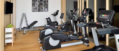 Un gimnasio con cintas de correr, elípticas y una bicicleta estática.