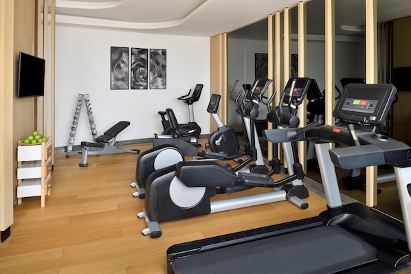 Un gimnasio con cintas de correr, elípticas y una bicicleta estática.