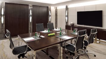 A conference room with a long table, six chairs, a flat-screen TV, and a wooden partition wall.