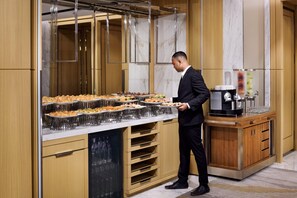 A buffet setup with multiple serving dishes, a coffee machine, and a wooden cabinet. - Crowne Plaza Jeddah Al Salam (Jeddah)