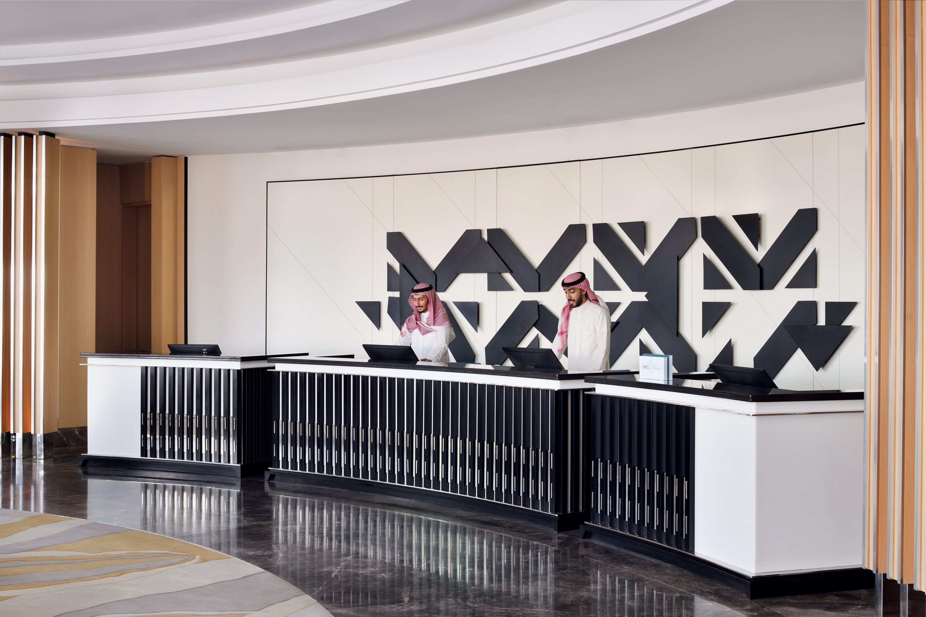 Un mostrador de recepción de diseño moderno, con un patrón geométrico en la pared y una encimera elegante y curvada.